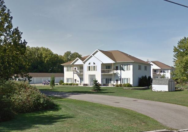 A large white house with a brown roof and a driveway in front.